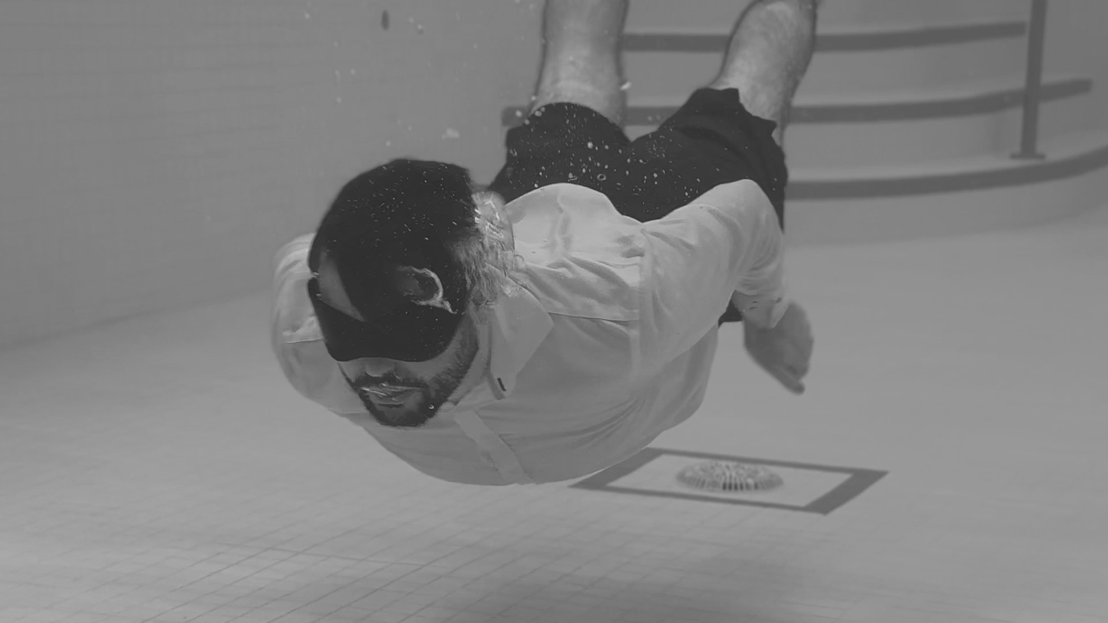 Black-and-white still of a figure diving mid-air