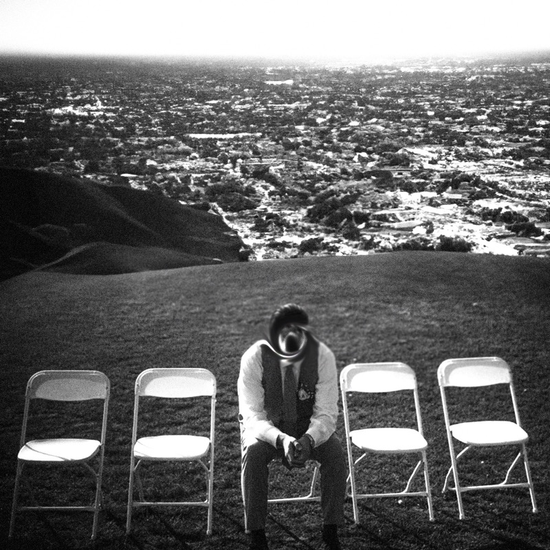 Black-and-white photo of a figure beside empty folding chairs on a hill