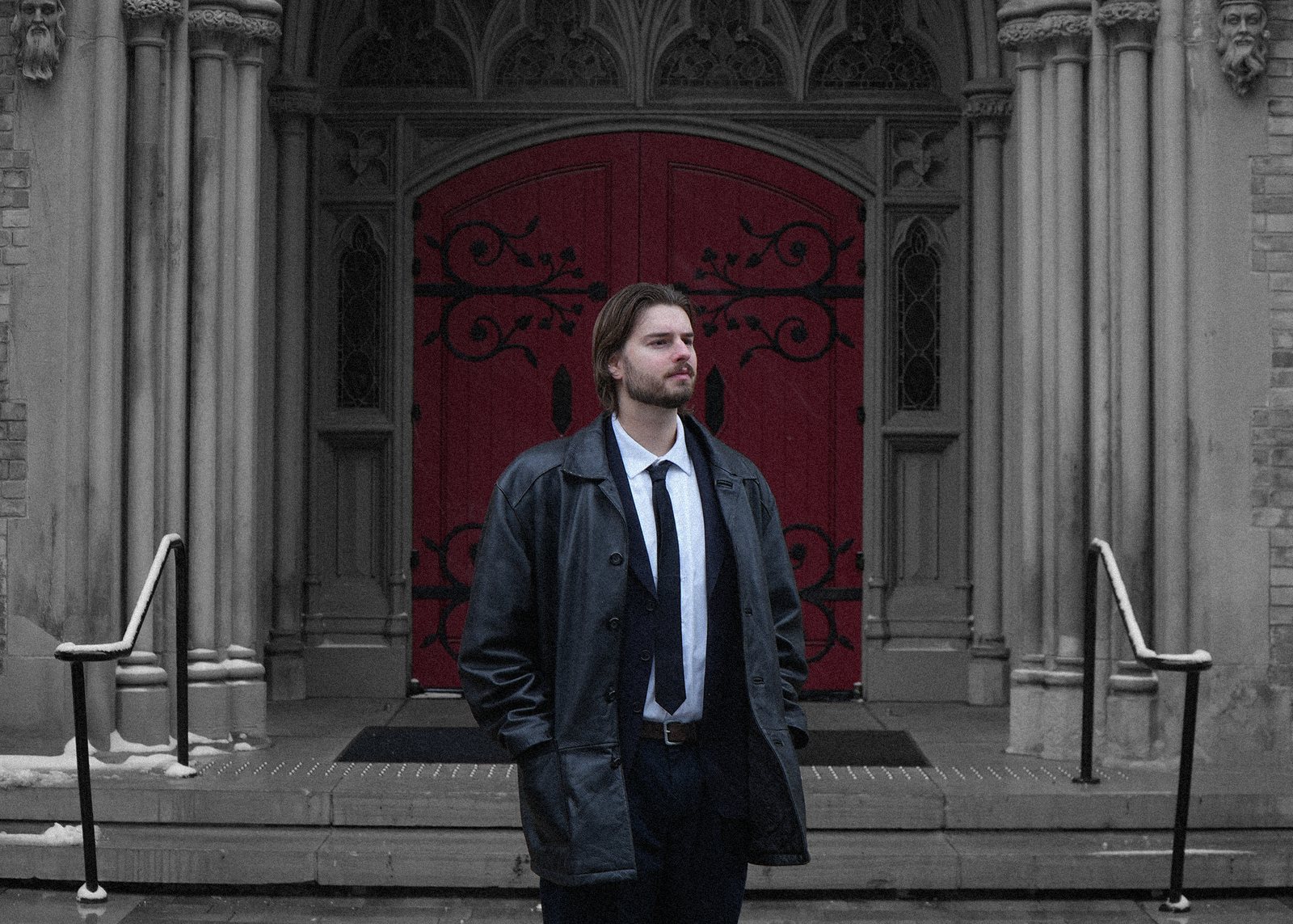 Black-and-white promo photo of Quinn Mills before a red church door