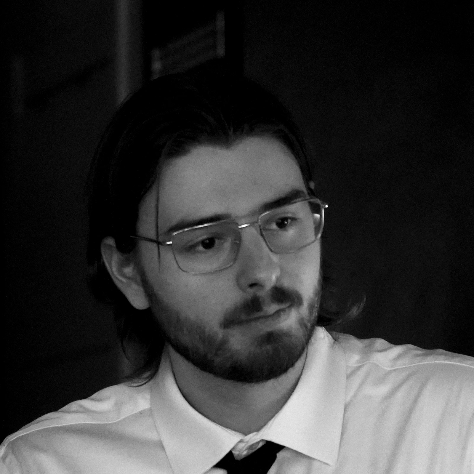 Black-and-white portrait of Quinn Mills in glasses and a tie